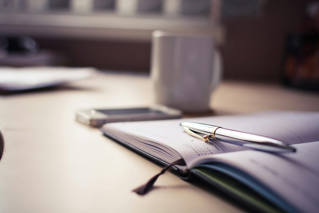 Tasse de café, agenda et stylo posés sur un bureau